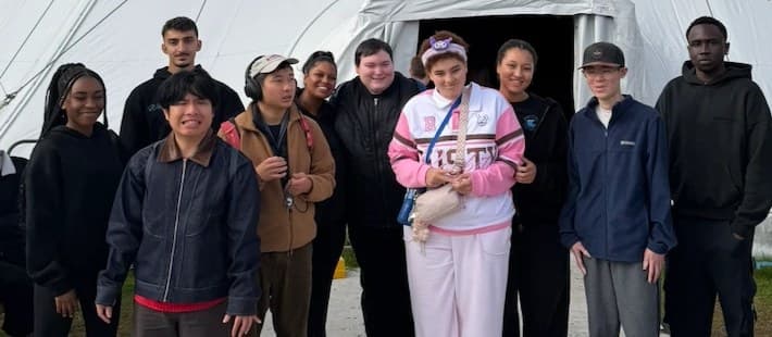 Participants and support workers smiling together outside a marquee