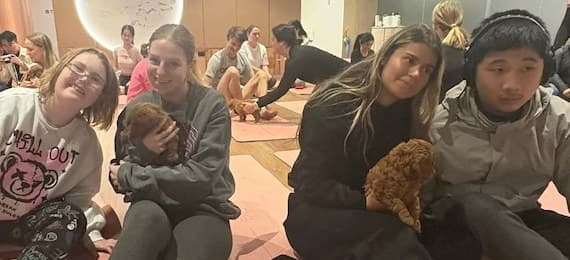 A group on yoga mats holding puppies, smiling at the camera