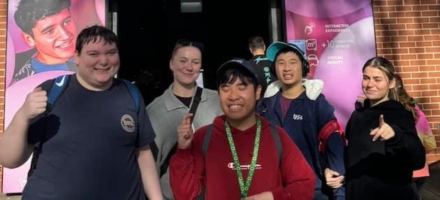A group of participants and support workers smiling outside an event